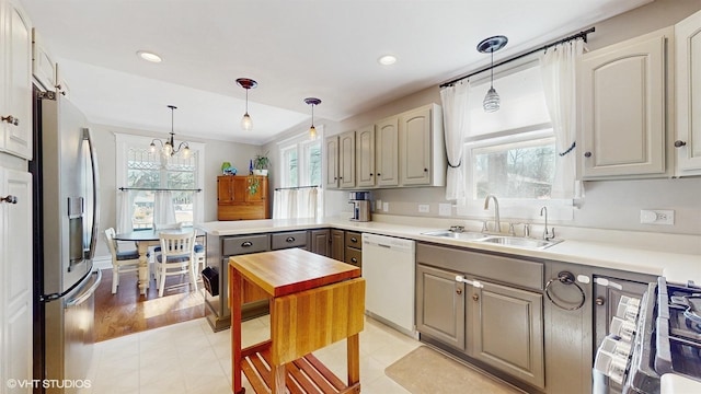 kitchen with a wealth of natural light, stainless steel appliances, light countertops, and a sink