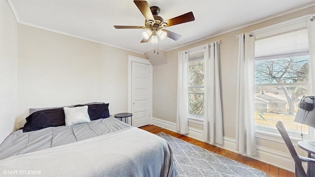 bedroom with ceiling fan, baseboards, wood finished floors, and crown molding