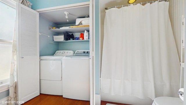 clothes washing area featuring laundry area, independent washer and dryer, and wood finished floors