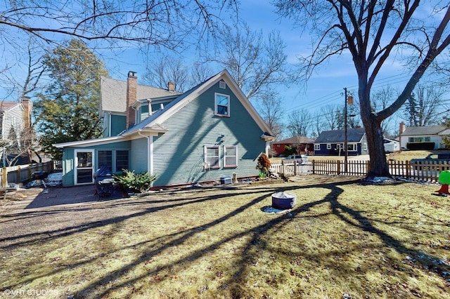 view of property exterior with a lawn, a chimney, and fence