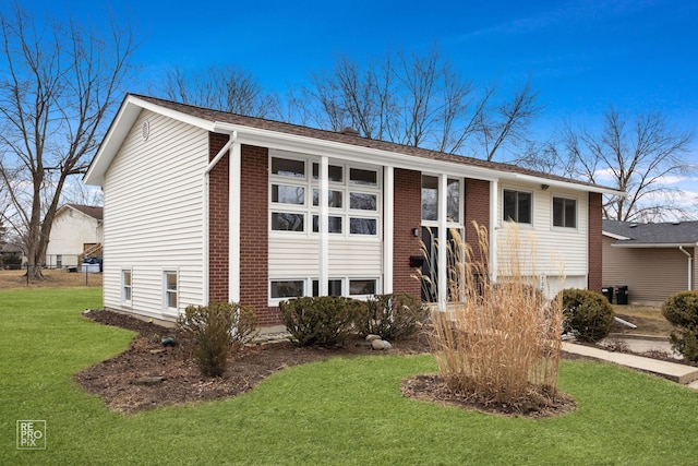 view of front facade with brick siding, a garage, and a front yard