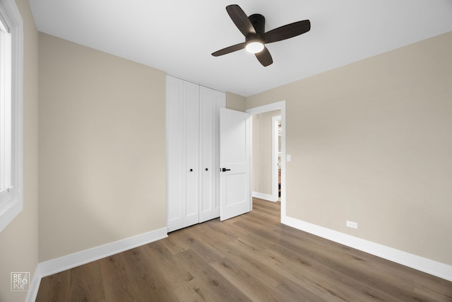 unfurnished bedroom featuring a closet, ceiling fan, baseboards, and wood finished floors