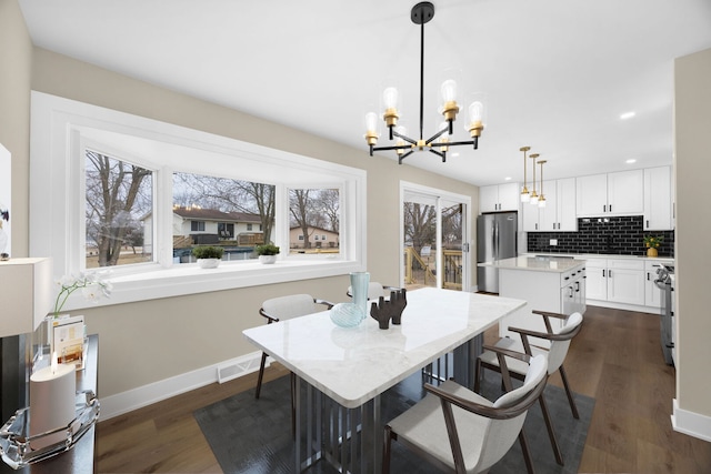 dining room featuring dark wood finished floors, visible vents, baseboards, and a chandelier