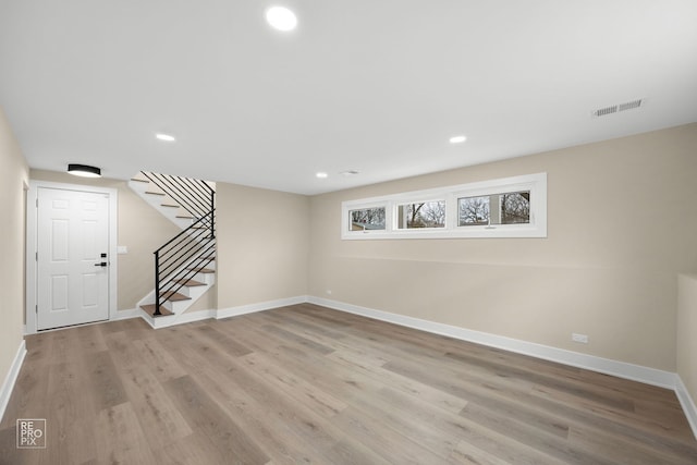 basement featuring visible vents, light wood-style flooring, stairs, and baseboards