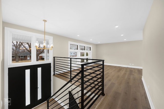 corridor featuring an upstairs landing, a chandelier, baseboards, and wood finished floors