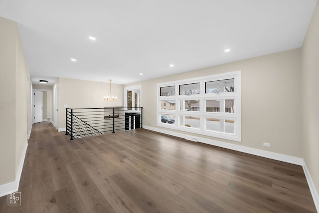 spare room featuring wood finished floors, visible vents, baseboards, recessed lighting, and a chandelier