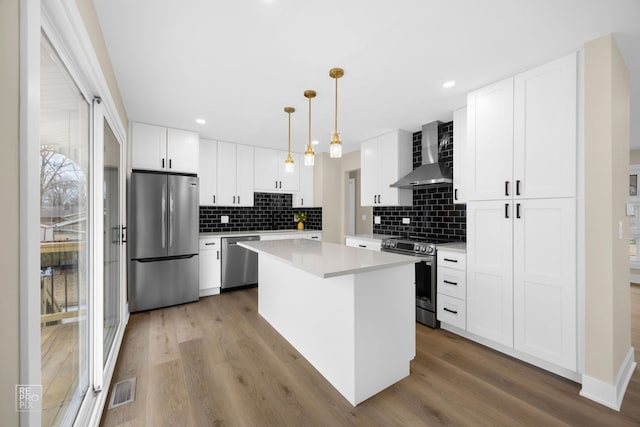 kitchen with visible vents, light countertops, appliances with stainless steel finishes, wood finished floors, and wall chimney exhaust hood