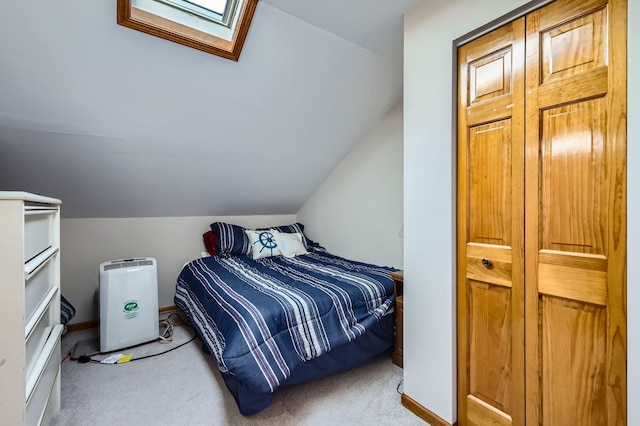 carpeted bedroom with lofted ceiling with skylight and baseboards