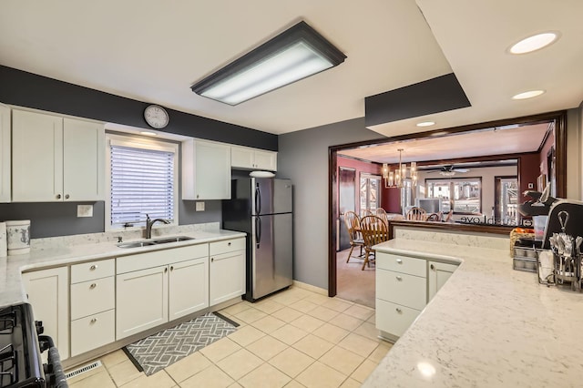 kitchen with a sink, light tile patterned floors, white cabinets, and freestanding refrigerator