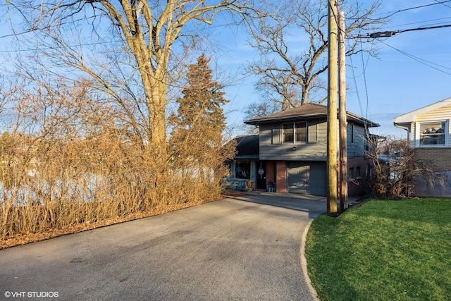 view of front facade featuring a front yard, brick siding, a garage, and driveway