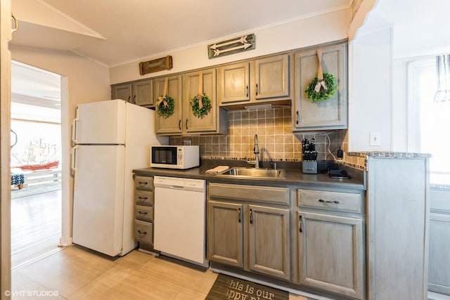 kitchen with dark countertops, decorative backsplash, white appliances, and a sink