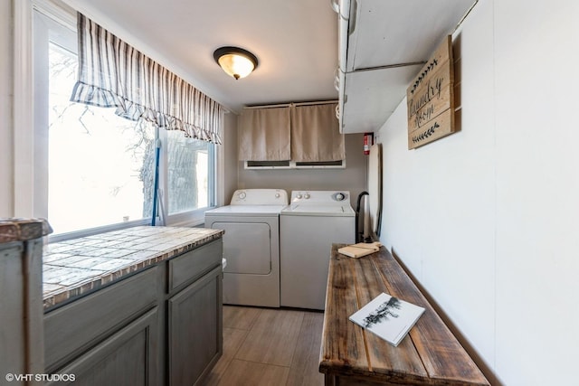 laundry area with cabinet space, wood finished floors, and separate washer and dryer