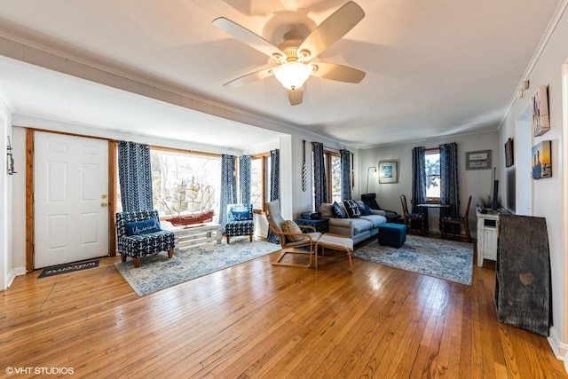 living area with hardwood / wood-style flooring, a ceiling fan, and ornamental molding