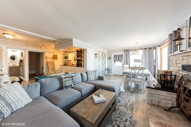 living room with a fireplace, stacked washer / drying machine, and light wood finished floors