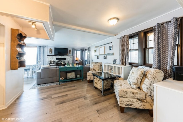 living room with a stone fireplace and wood finished floors