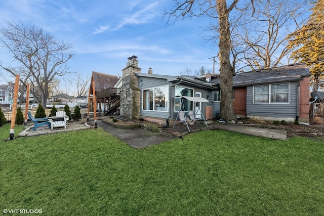 rear view of house with stairway, a lawn, and a chimney