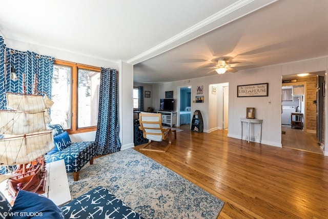 living area with ceiling fan, baseboards, hardwood / wood-style floors, and crown molding