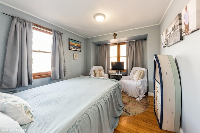 bedroom featuring multiple windows, wood finished floors, and ornamental molding