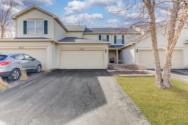 view of front of house featuring a shingled roof, a front yard, and driveway