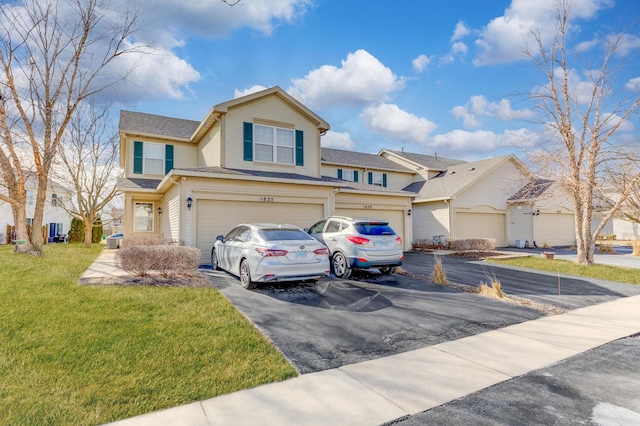 traditional-style home featuring a garage, aphalt driveway, and a front yard