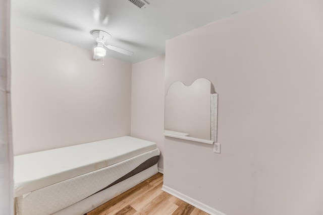 bedroom featuring a ceiling fan, visible vents, baseboards, and wood finished floors