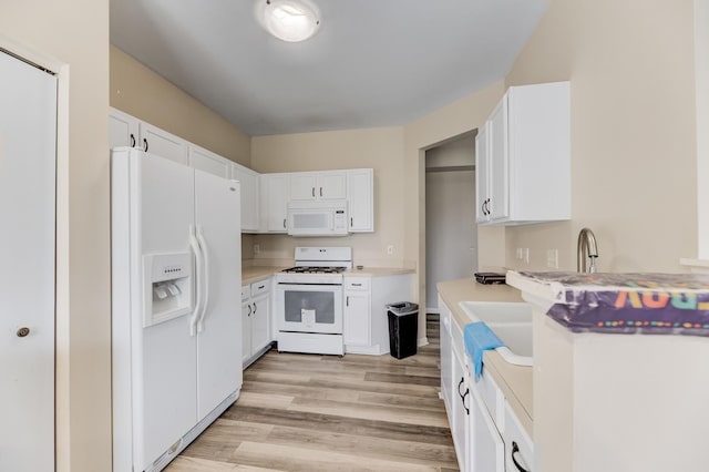 kitchen with white appliances, light wood-type flooring, and white cabinets