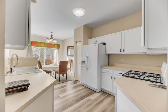 kitchen with light wood-style flooring, white refrigerator with ice dispenser, a sink, white cabinets, and light countertops