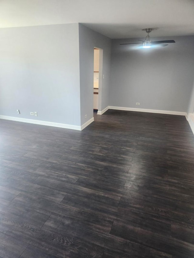 empty room with dark wood-style floors, baseboards, and a ceiling fan