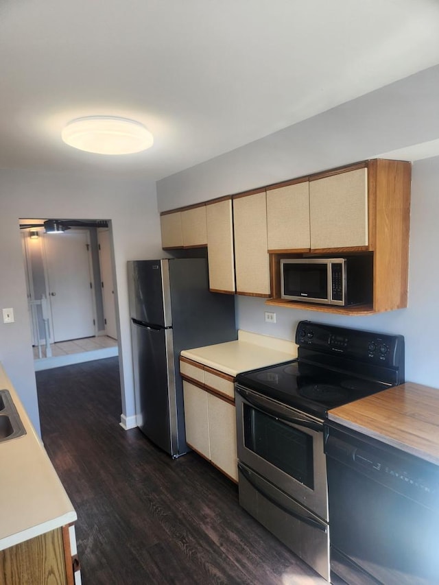 kitchen featuring stainless steel appliances, light countertops, dark wood finished floors, and cream cabinets