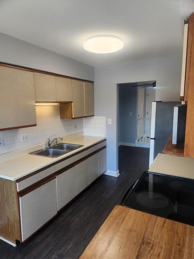 kitchen with dark wood-style floors, light countertops, black electric range oven, backsplash, and a sink