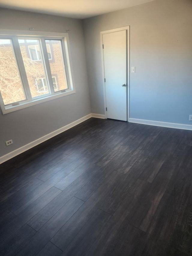 spare room featuring dark wood finished floors and baseboards