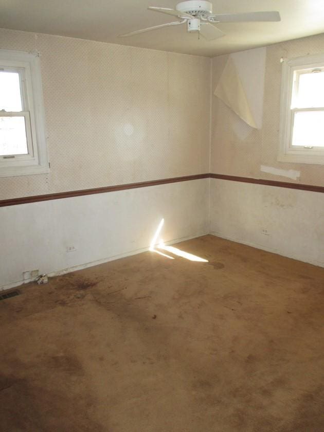 empty room featuring ceiling fan, carpet floors, and wallpapered walls