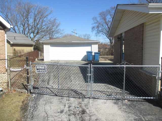 view of side of property featuring brick siding, a detached garage, fence, and an outbuilding