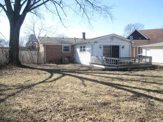 back of property featuring a deck, central air condition unit, brick siding, fence, and a lawn