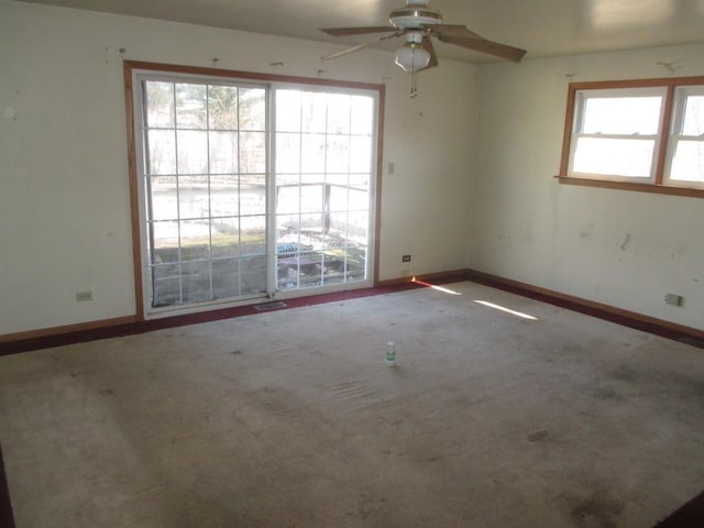 carpeted empty room featuring ceiling fan and baseboards