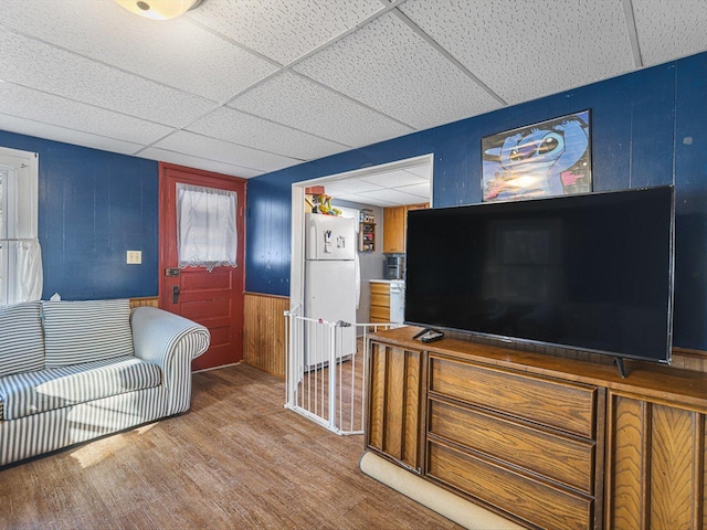 living room with wood walls, wood finished floors, and a paneled ceiling