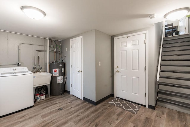 laundry area with washer / clothes dryer, electric water heater, a sink, wood finished floors, and laundry area