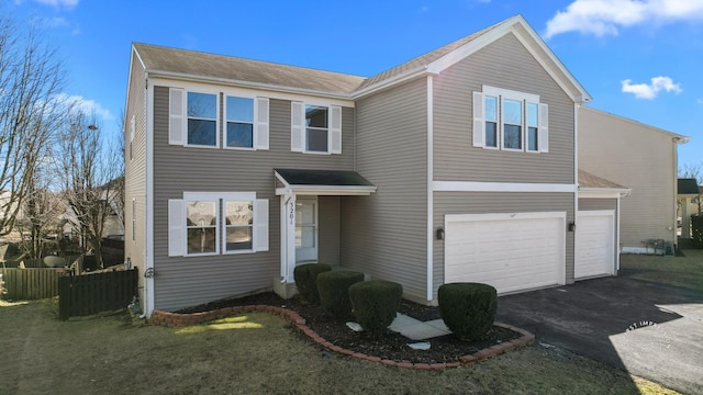 traditional home featuring driveway, a garage, fence, and a front lawn