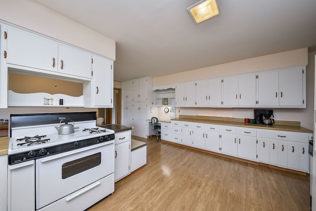 kitchen with white gas stove, open shelves, light wood-type flooring, and white cabinetry