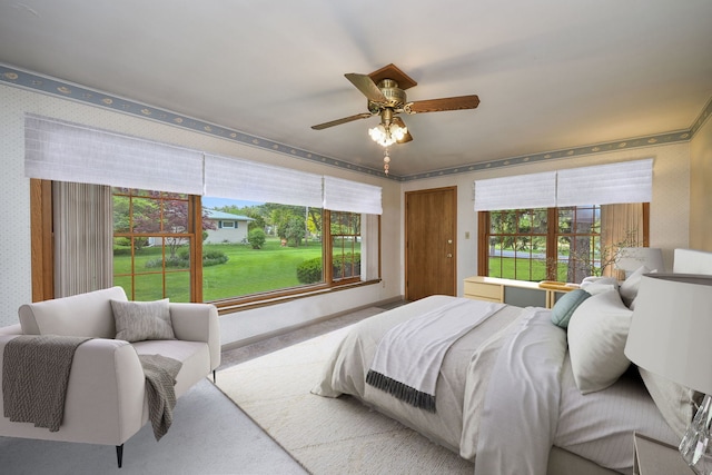 bedroom with wallpapered walls, multiple windows, and a ceiling fan