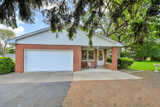 view of front facade with asphalt driveway, brick siding, an attached garage, and a front yard
