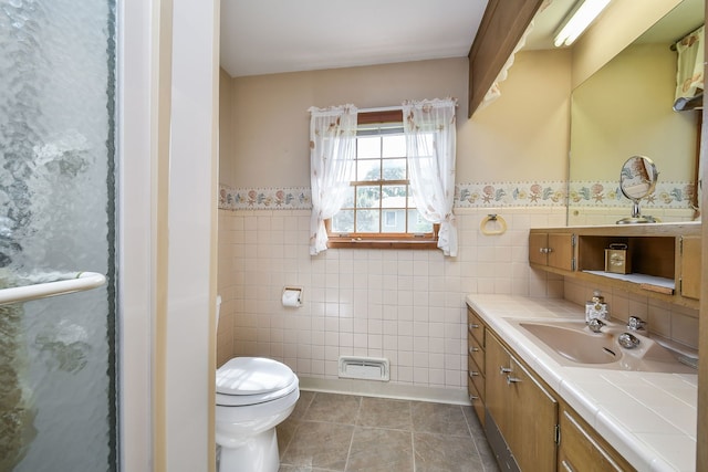 full bathroom with tile walls, toilet, wainscoting, tile patterned floors, and vanity