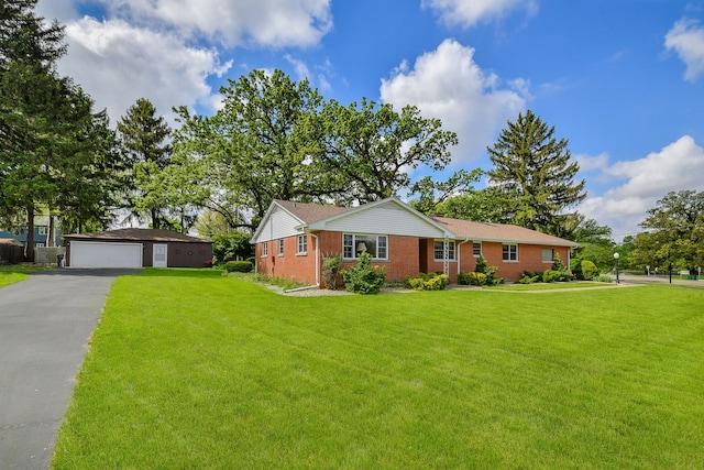 ranch-style home with an outbuilding, brick siding, a garage, and a front yard