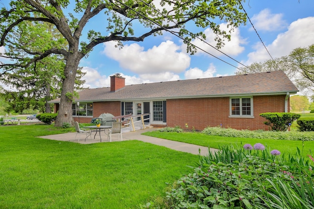 back of property featuring brick siding, a patio area, a chimney, and a lawn