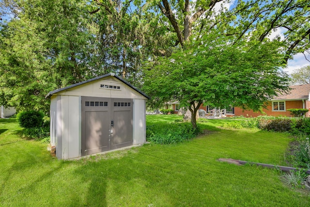 view of green lawn featuring a storage shed and an outdoor structure