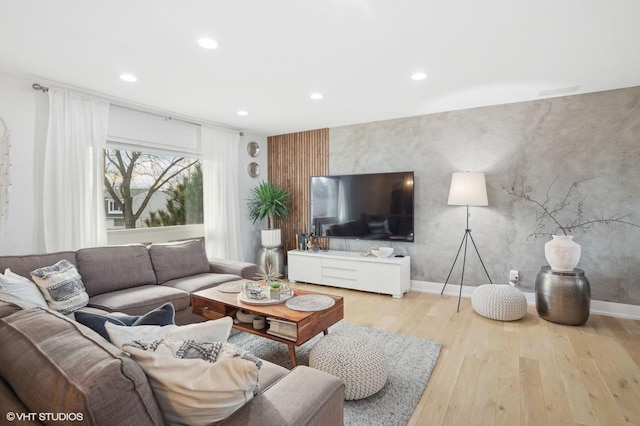 living area with an accent wall, baseboards, wood finished floors, and recessed lighting