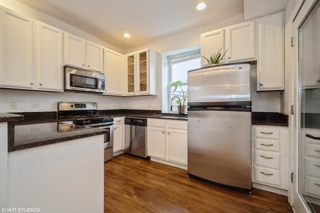 kitchen with stainless steel appliances, white cabinets, a sink, and dark wood-style floors