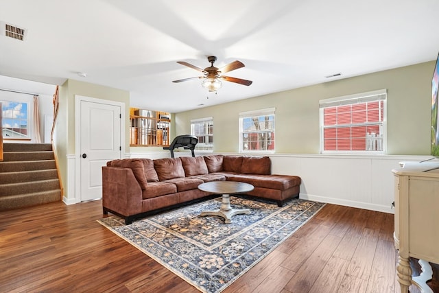 living room featuring stairway, wood finished floors, visible vents, and a ceiling fan