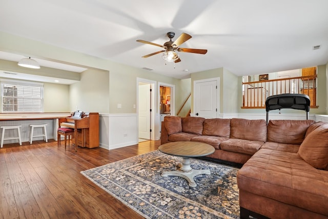 living room with hardwood / wood-style flooring, ceiling fan, visible vents, and wainscoting