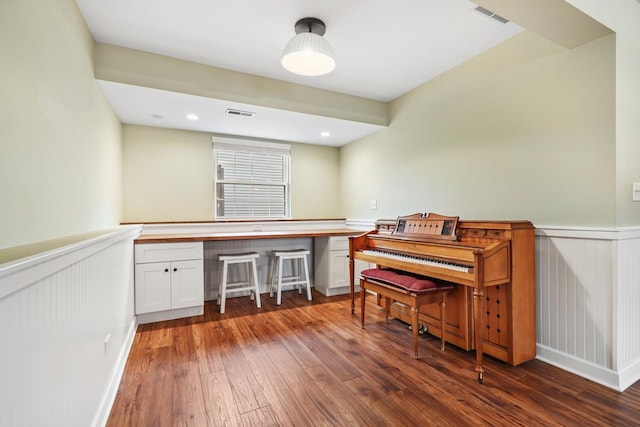 office space with a wainscoted wall, wood-type flooring, visible vents, and recessed lighting